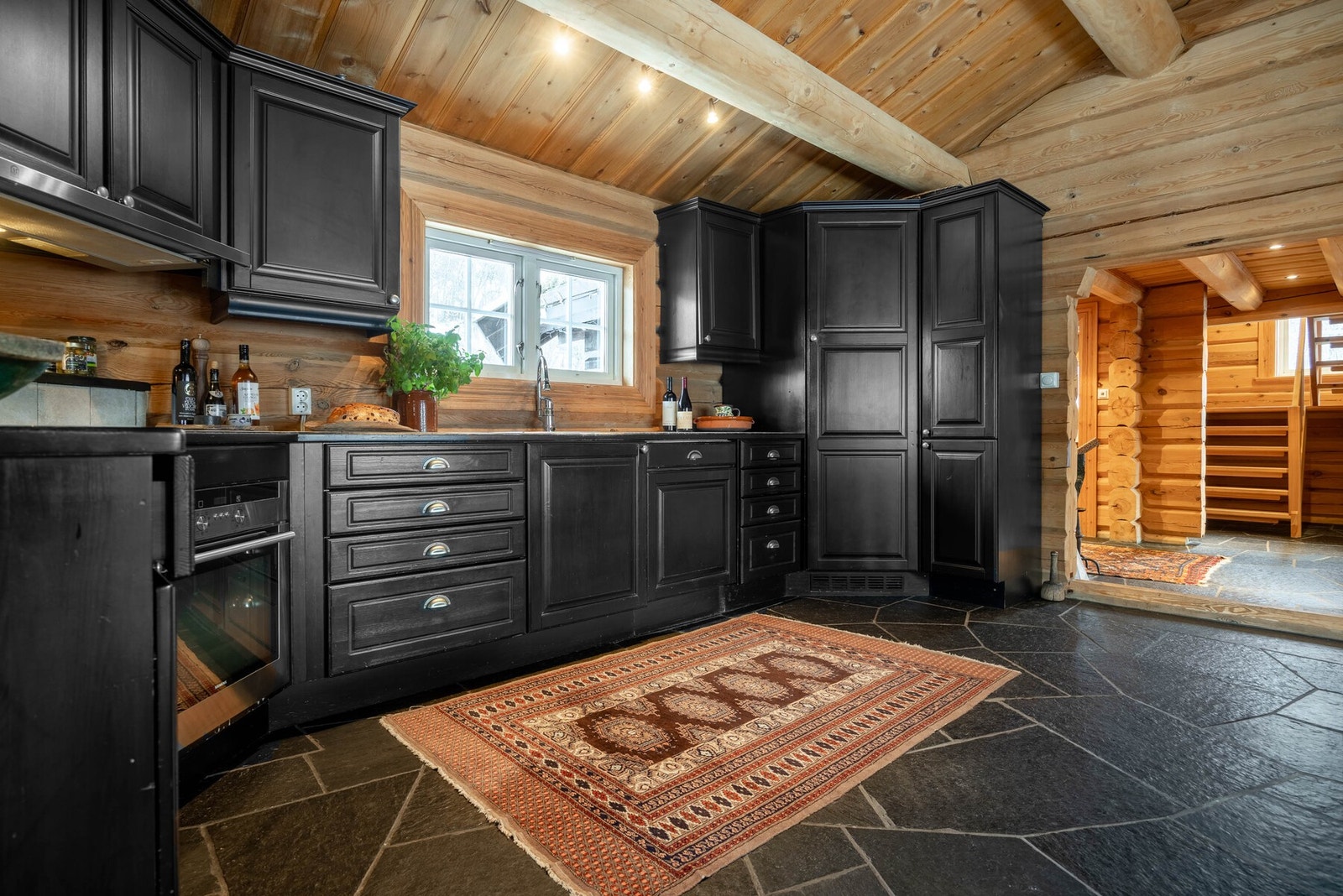 Kjøkkenet kombinerer robuste materialvalg med moderne funksjonalitet, og passer perfekt til fjellhyttas lune fjellatmosfære. Stort praktisk kjølehjørne. Galleribilde