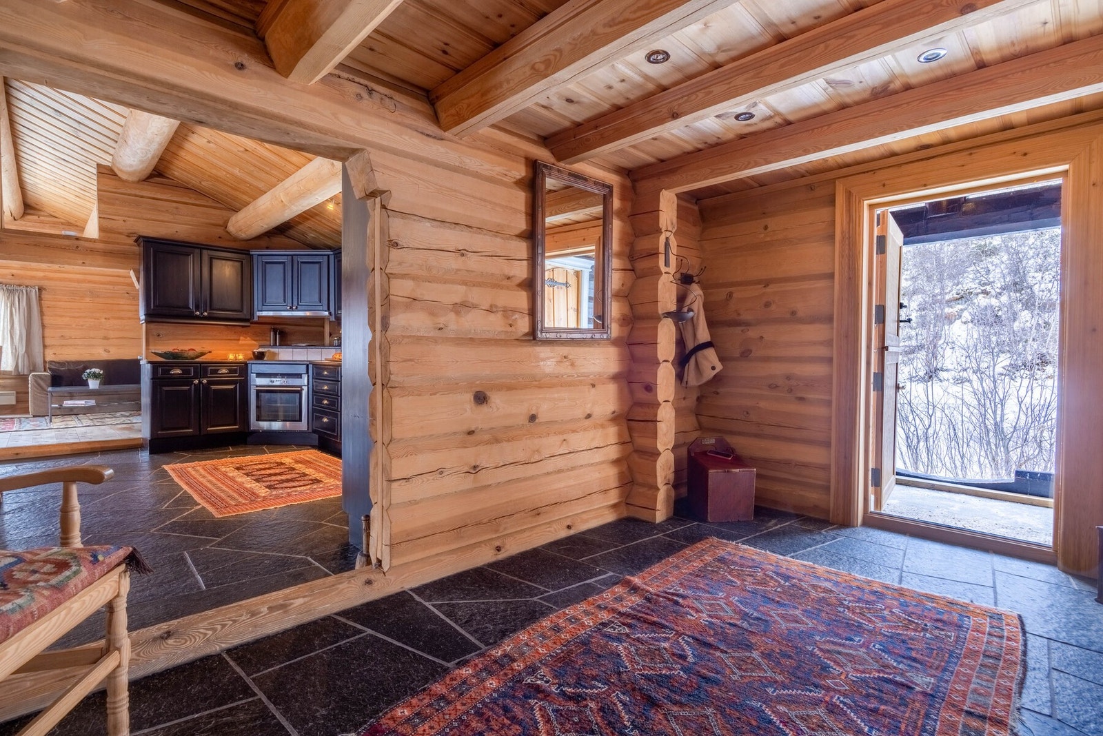 I den store hallen møtes naturlige materialer i perfekt harmoni: Massiv tømmerkonstruksjon og røft skifergulv. Galleribilde