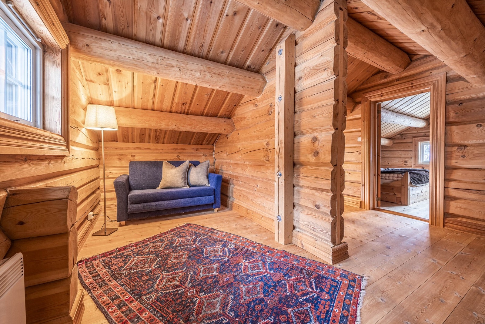 Loftstuen inviterer til ro og hyttekos, med varme tømmervegger og myke kroker for avslapning. Galleribilde