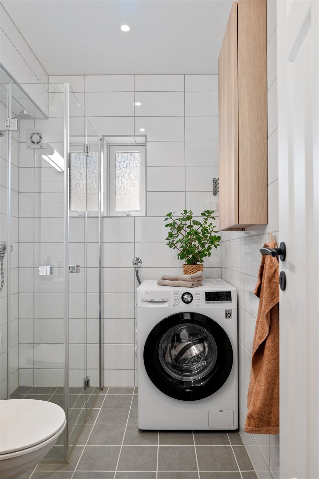 Badet er innredet med vegghengt toalett, dusjhjørne med glassdører, servant med underskap og speil, samt opplegg til vaskemaskin. Galleribilde