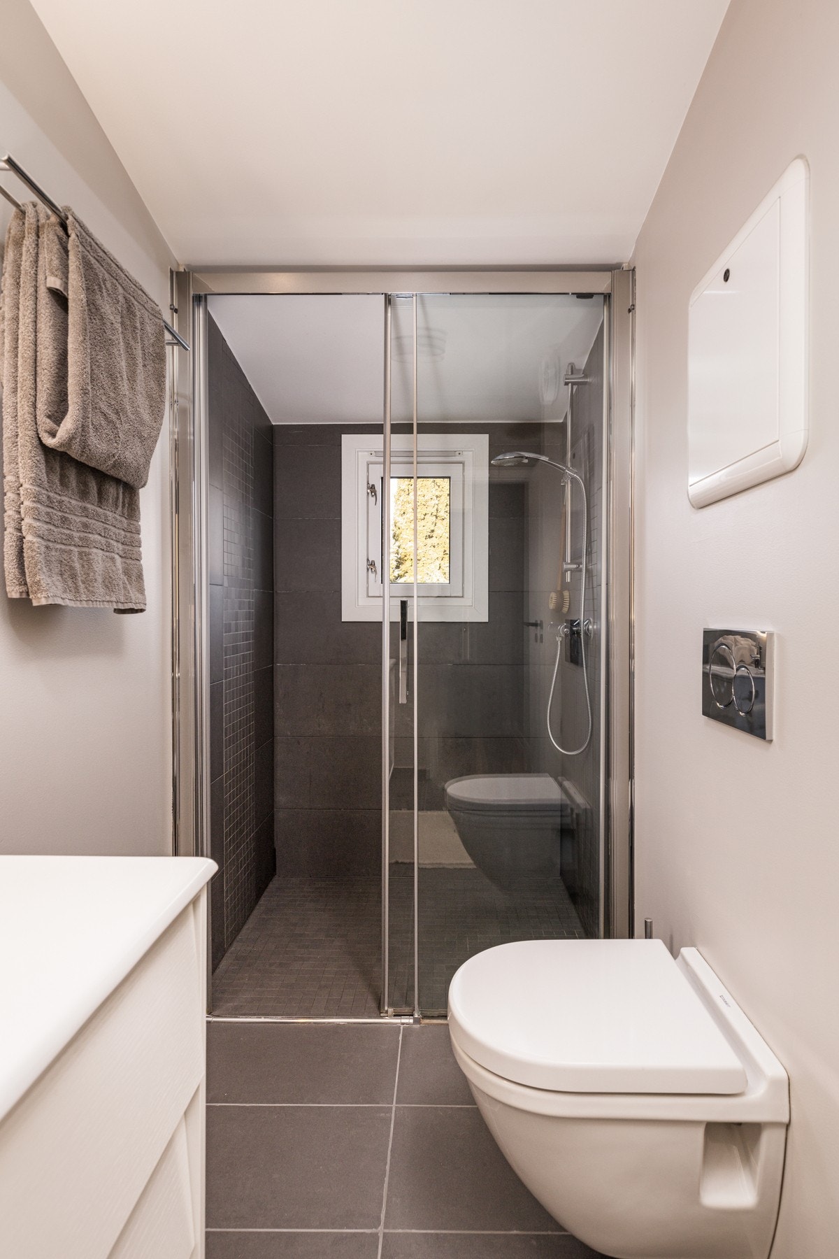 Rommet har dusj med skyvedører i herdet glass, servant og veggfestet toalett med innebygget sisterne. Galleribilde