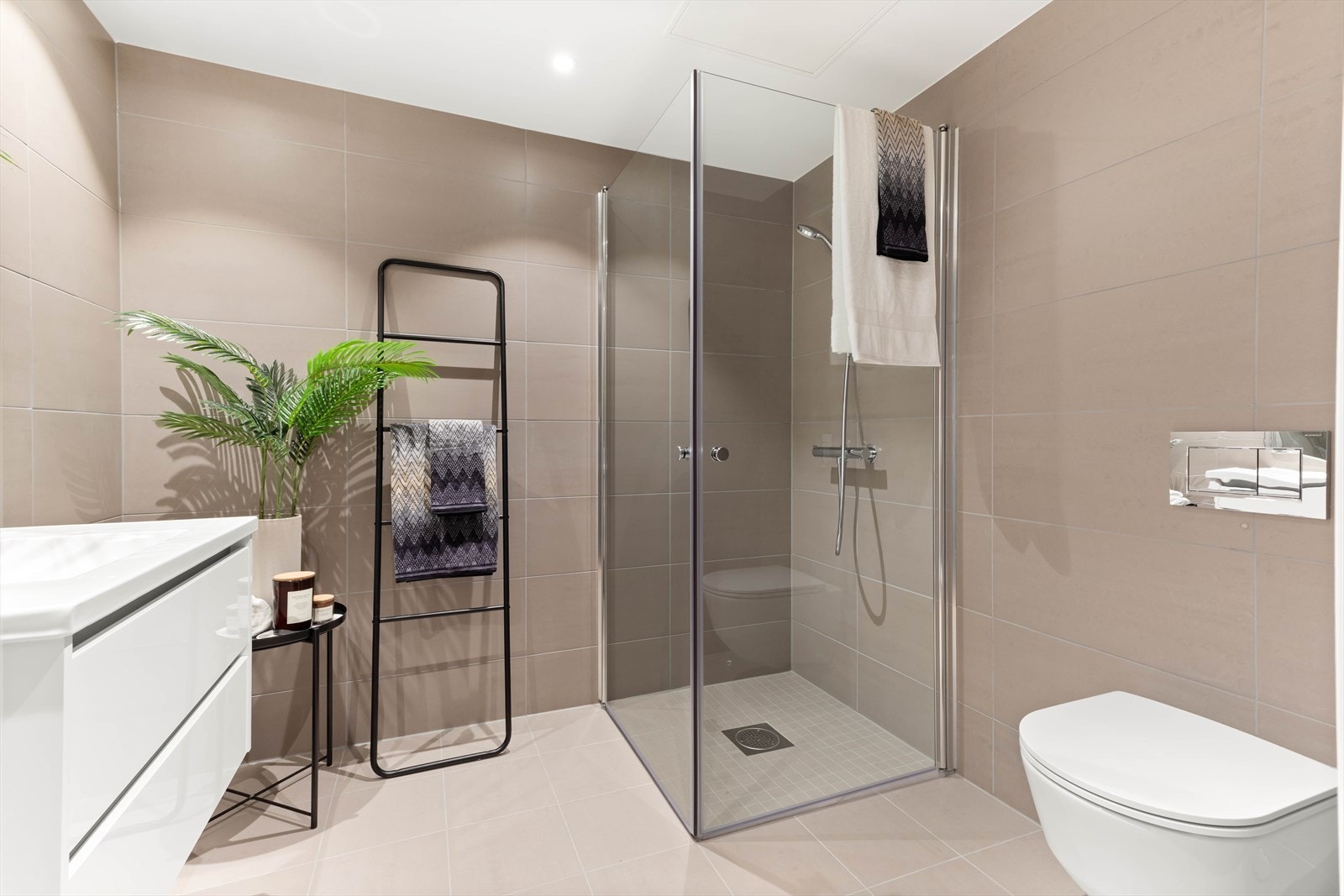 Innredningen består av vegghengt servantskap med speil over servant, vegghengt toalett og dusjhjørne med glassdører. Galleribilde