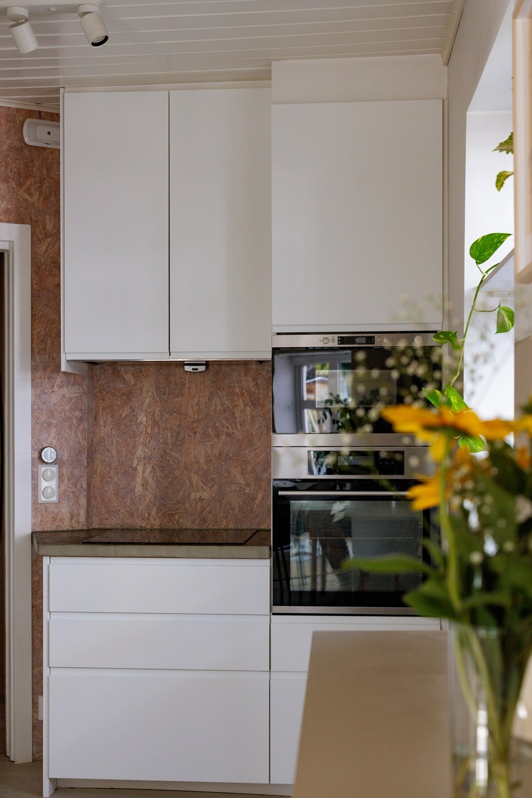 Kjøkkeninnredningen består av en stilren kombinasjon av hvite matte fronter med integrert grep, støpt benkeplate i betong og integrerte hvitevarer som platetopp, stekeovn, oppvaskmaskin og mikrobølgeovn Galleribilde