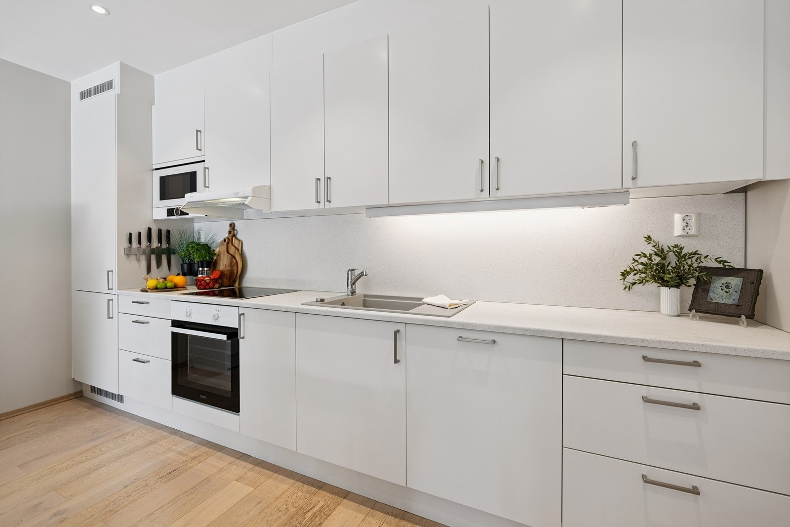 Kjøkkeninnredningen har glatte, lyse fronter og alle hvitevarer er integrert. Galleribilde