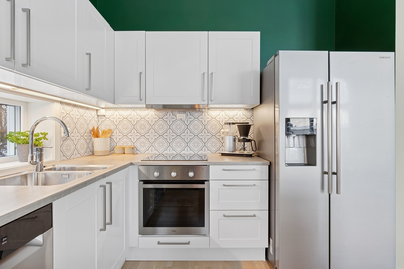 Pen kjøkkeninnredning med hvite fronter og integrerte hvitevarer. Galleribilde