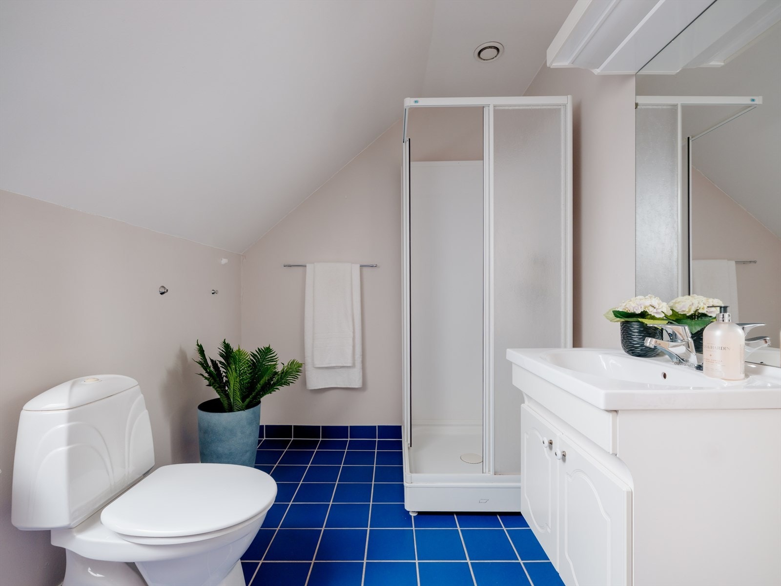 Badet er innredet med toalett, dusjkabinett og baderomsinnredning Galleribilde