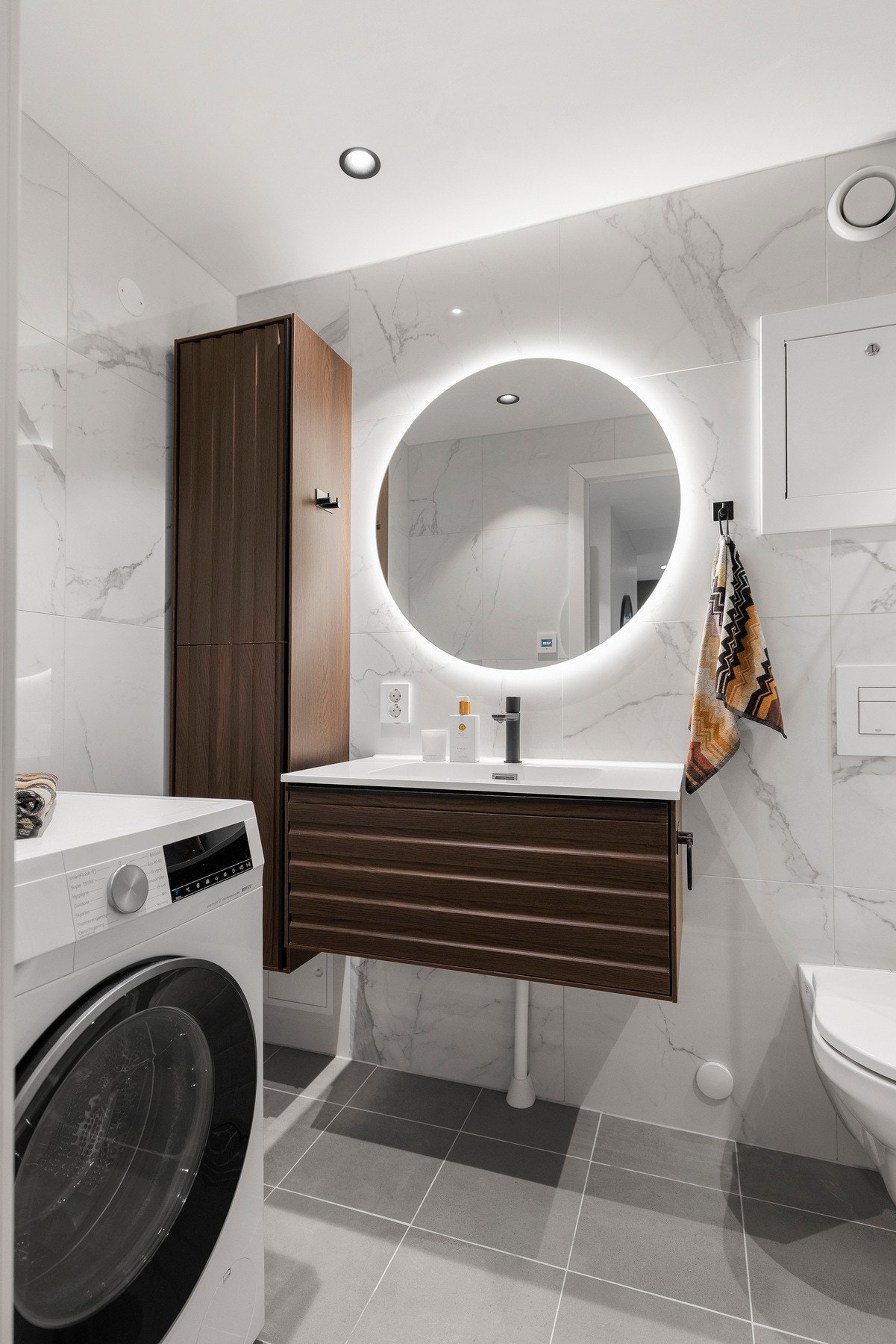 Rommet er innredet med servant, skap og speil med integrert lys Galleribilde