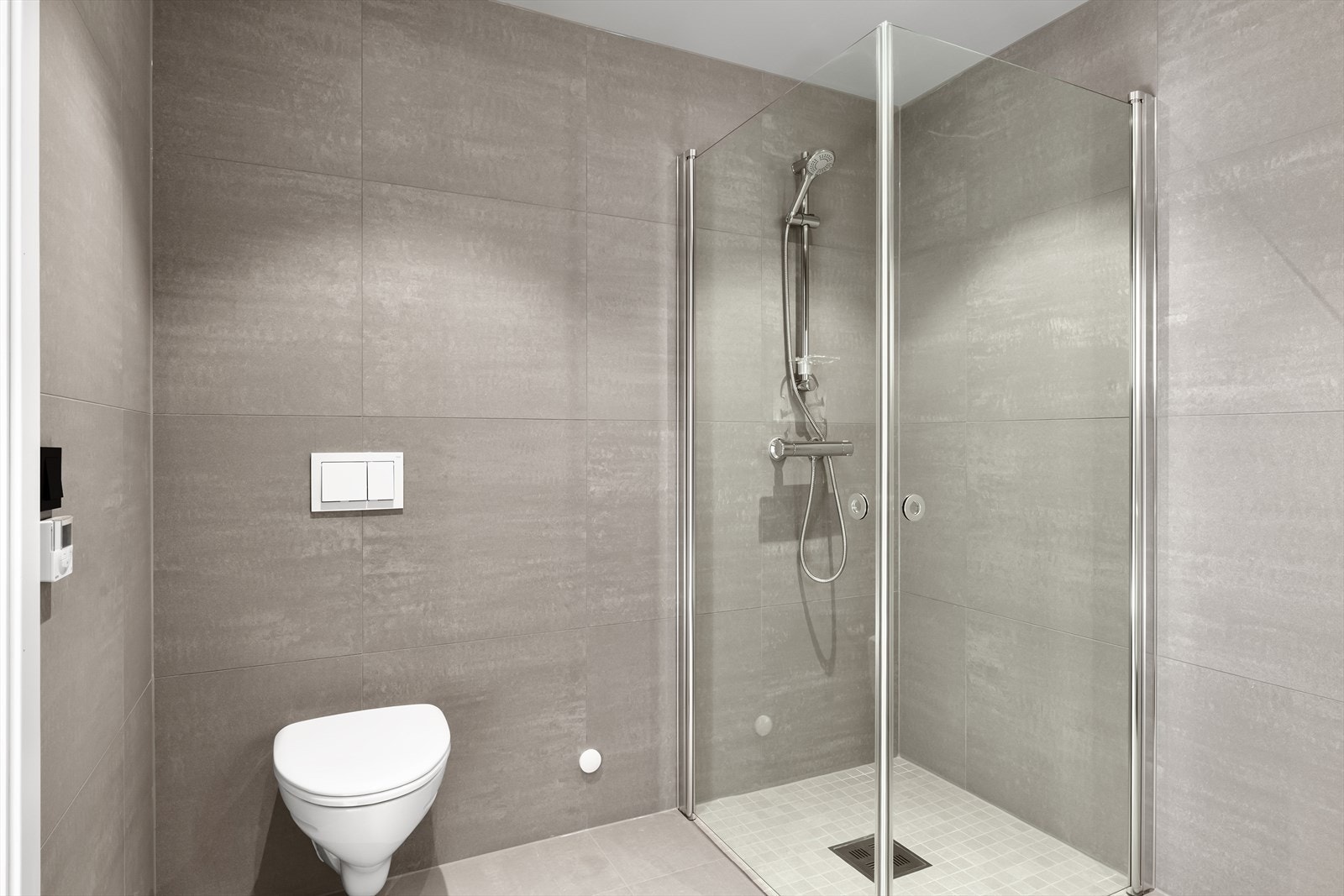 Flott helfliset bad med vegghengt wc, dusjhjørne og varme i gulv for ekstra komfort. Badet fremstår som arealeffektivt med pen baderomsinnredning i hvit utførelse. (bilde tatt fra H0204) Galleribilde