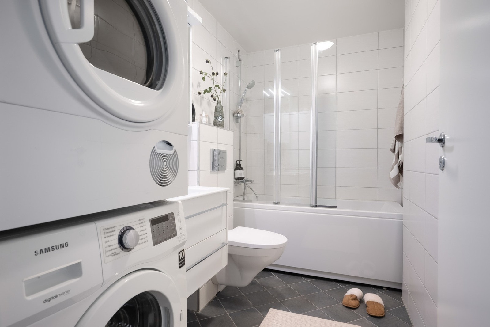 Badekar med leddet glassdør og opplegg for vaskemaskin. Elektriske varmekabler i gulv og mekanisk avtrekk. Galleribilde