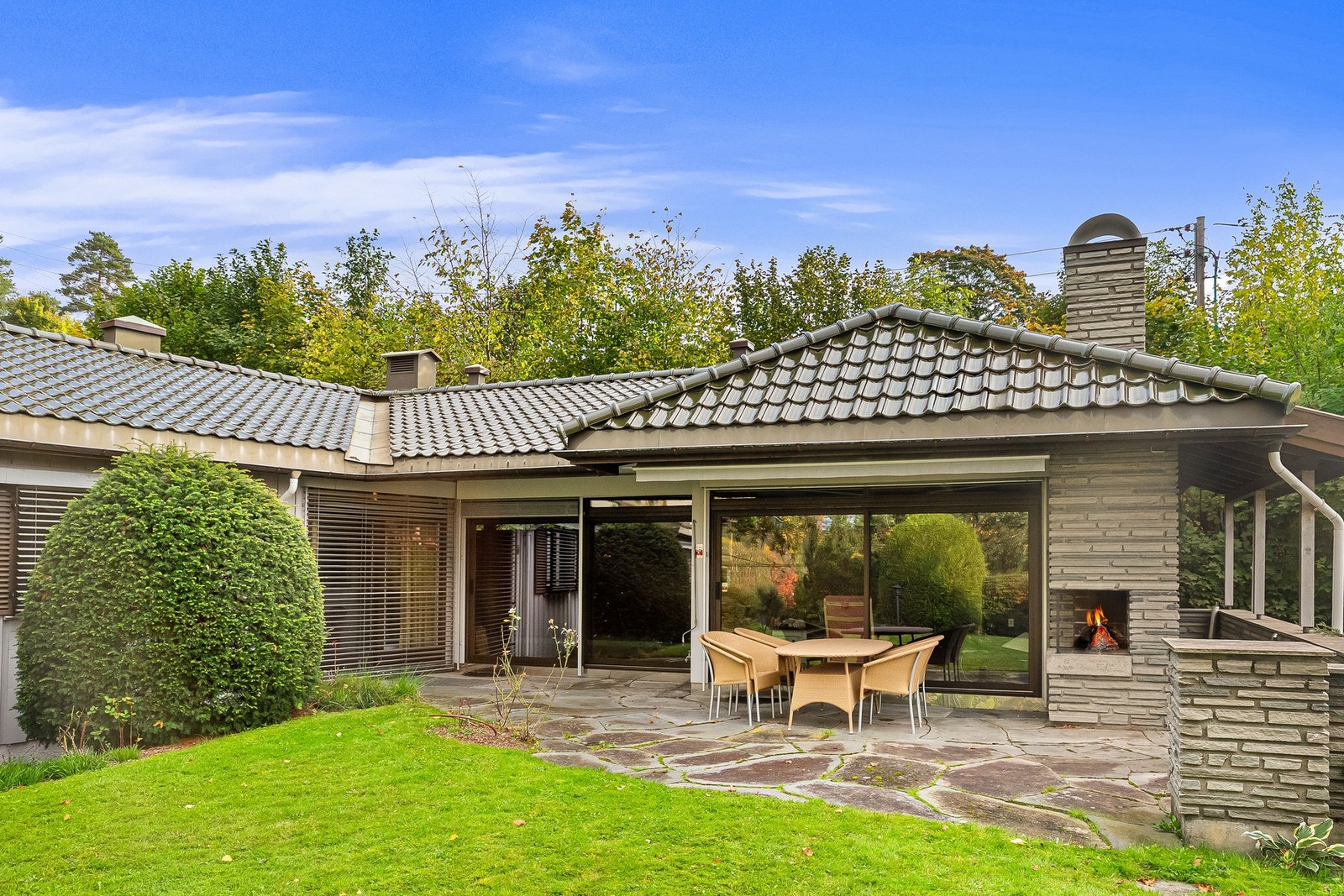 Utenfor bassengområdet er det en skiferterrasse med utepeis som gir hyggelig utemiljø Galleribilde