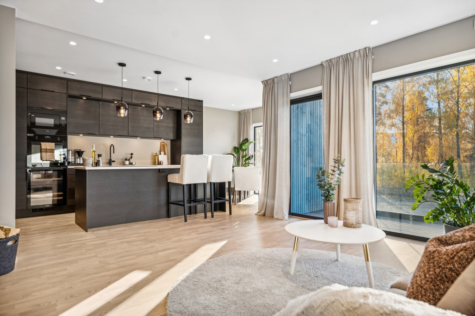 Åpen løsning mellom stue og kjøkken med ett moderne og tidløst kjøkken fra Sigdal med integrerte hvitevarer. Galleribilde