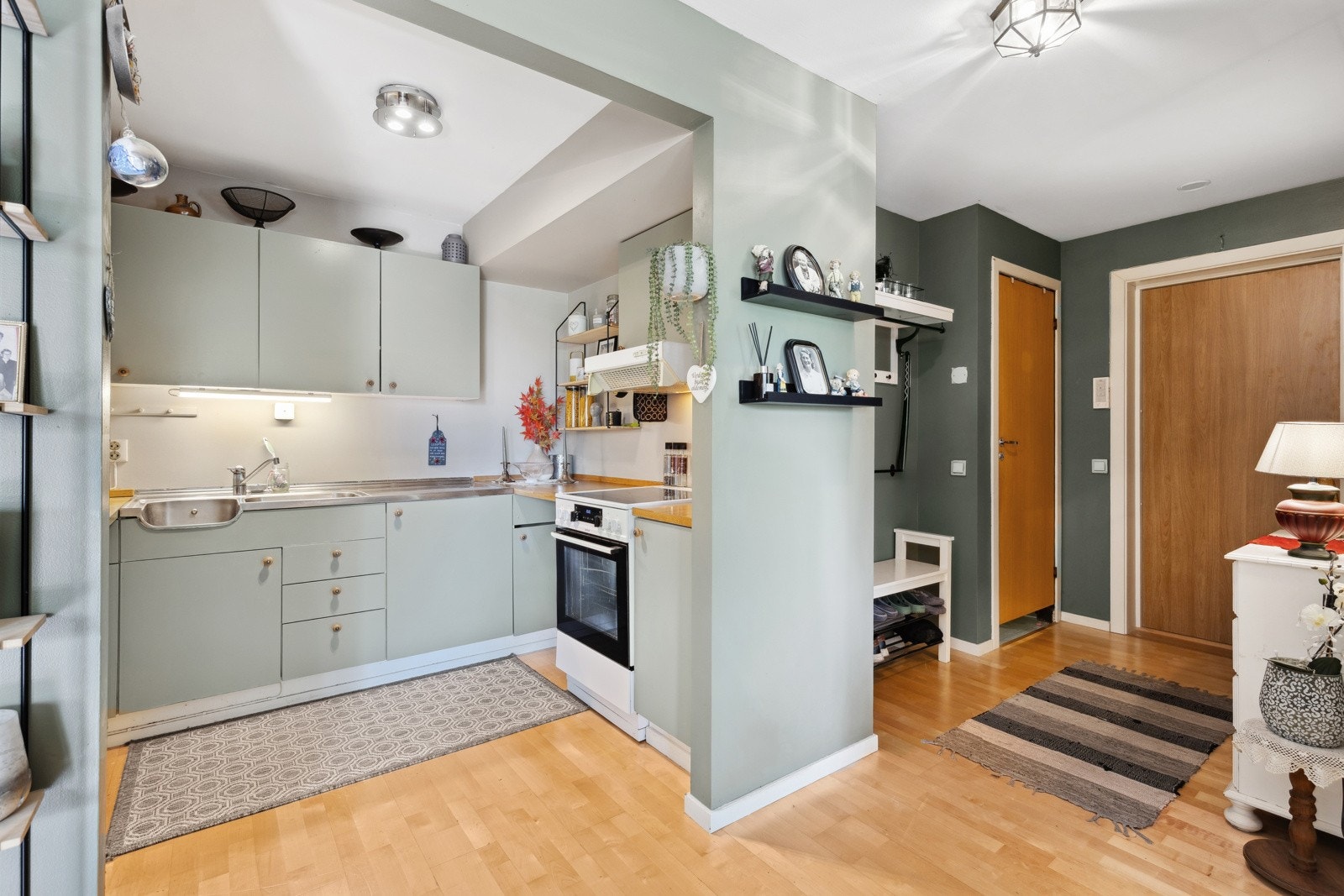 Kjøkkenet har en åpen løsning mot stuen og fremstår klassisk og funksjonelt - innredet med malte slette fronter, laminert benkeplate og helt benkebeslag med nedfelt vaskekum i rustfritt stål. Galleribilde