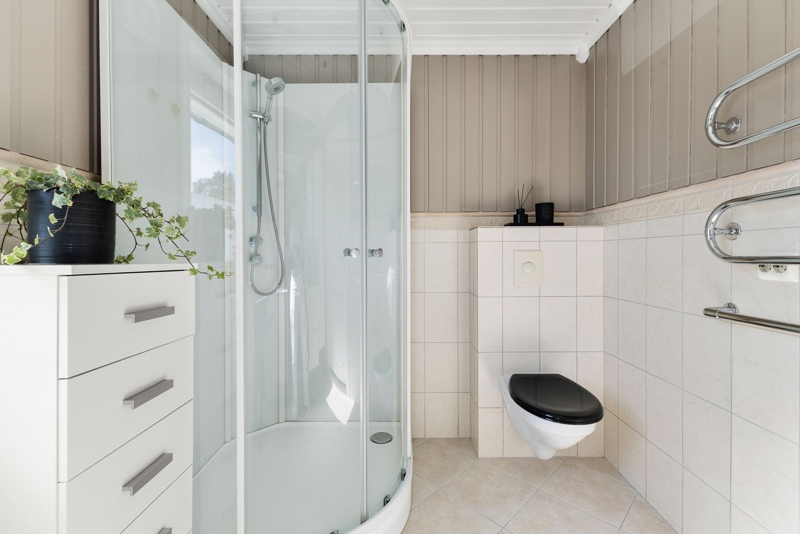 Badet er innredet med servant med innredning, oppbevaringsskap, dusjkabinett og vegghengt toalett Galleribilde