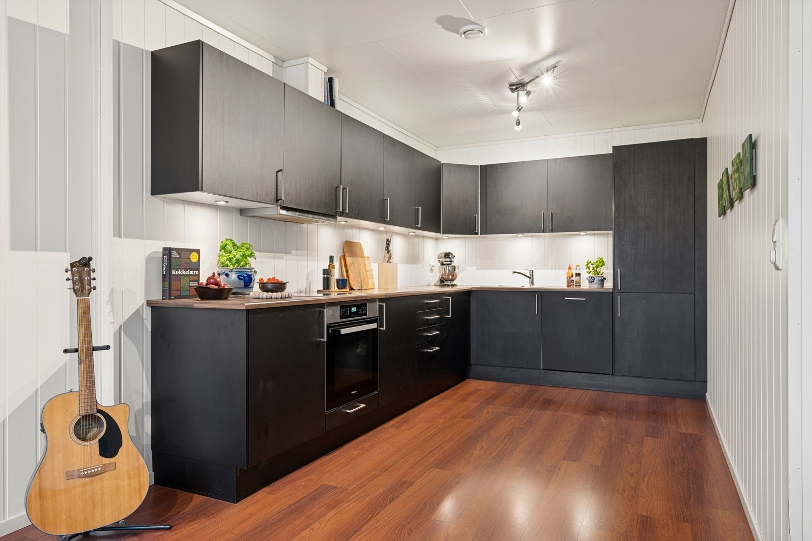 Kjøkkenet har en mørk utførelse, godt med skap- og benkeplass. Galleribilde