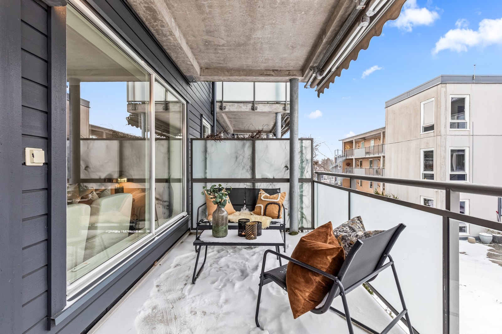 Solrik balkong med moderne rekkverk i stål og glass, fjernstyrt markise og god plass til sittegruppe. Galleribilde