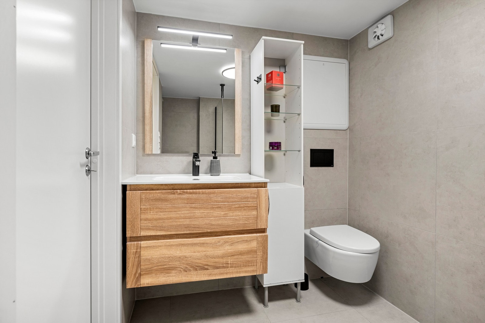 Her finner du servantskap med nedfelt servant, speil med lys, vegghengt toalett og dusjhjørne med glassvegg. Galleribilde