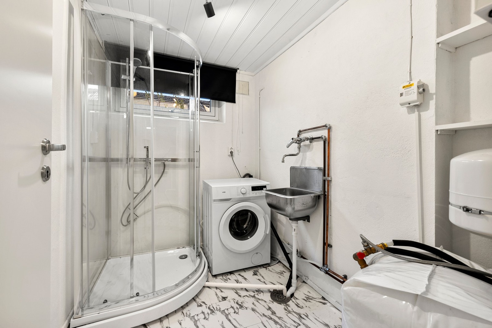 Vaskerommet har utslagsvask, opplegg for vaskemaskin og tørketrommel. Veggene er malt i hvit mur, og gulvet har belegg med sluk. Galleribilde