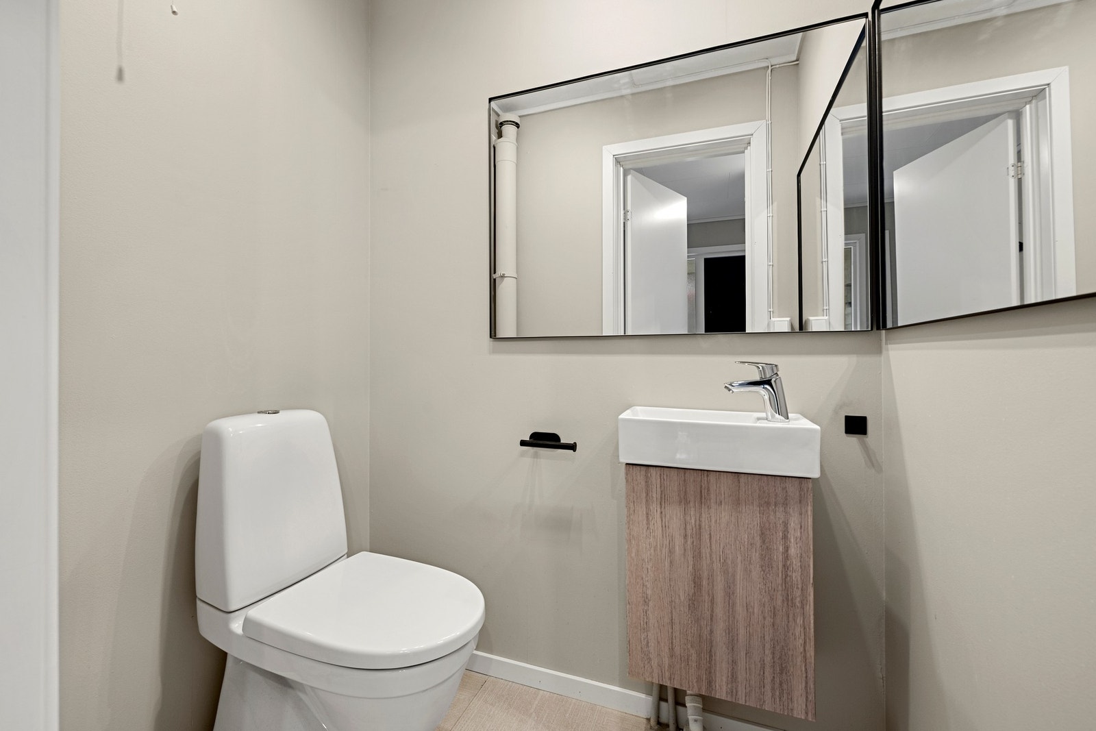 Et praktisk toalettrom med adkomst fra entréen. Rommet er innredet med servant, to speil og gulvmontert toalett. Galleribilde