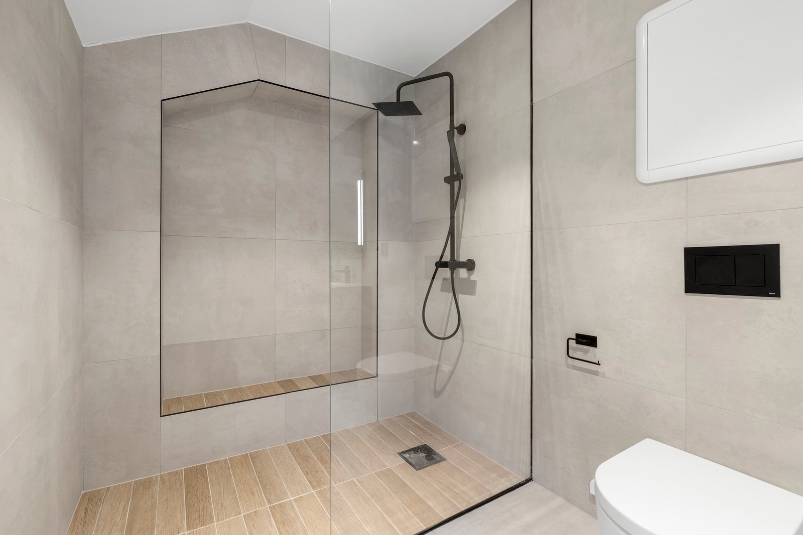 Stor dusjnisje med plassbygde hyller, doble servanter og god oppbevaringsplass gjør dette til et funksjonelt og innbydende familiebad. Galleribilde