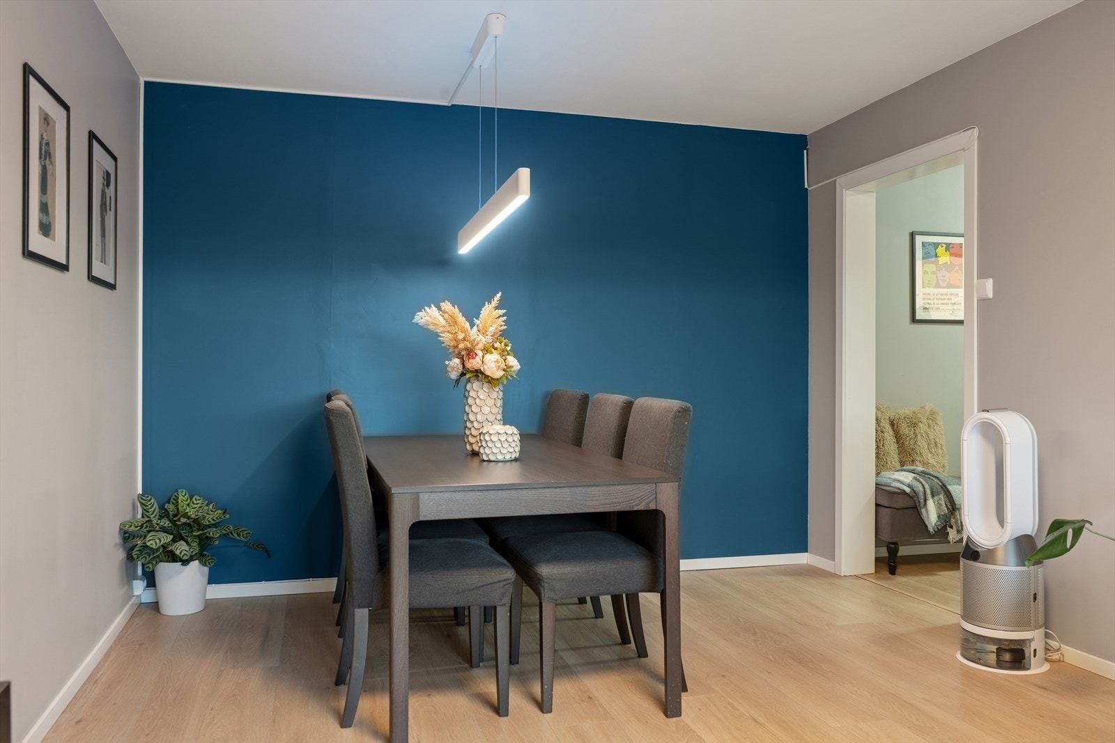 Romslig stue med naturlig inndeling for sitte- og spisegruppe, fremhevet av en stilfull kontrastvegg. Galleribilde