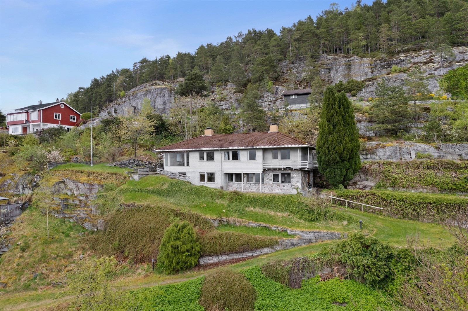 Tomta er pent opparbeidd med murar og plen på fleire nivå. Galleribilde