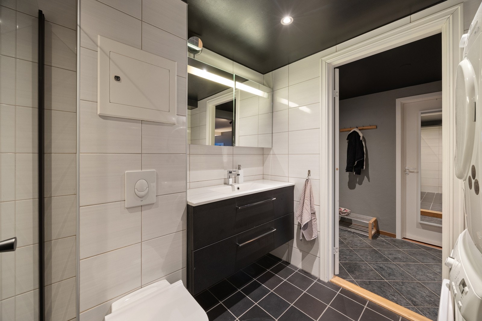 Badet har moderne servantmøblement med to skuffer, speilskap med integrert belysning og tilhørende veggskap. Separat dusjhjørne med regnfallsdusj og innfellbare glassdører, samt vegghengt toalett. Galleribilde