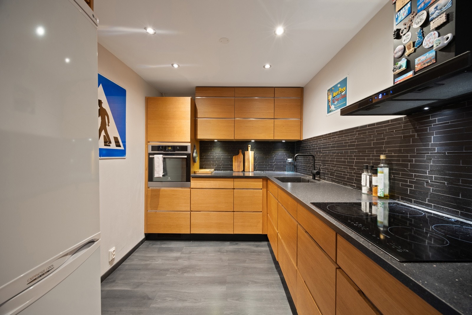 Stilrent kjøkken fra Kvik, nytt i 2013, med praktisk vinkelløsning som gir rikelig benke- og arbeidsplass. Innredningen har slette fronter i imitert eik, laminat benkeplate og nedfelt kum i mørk kompositt. Galleribilde