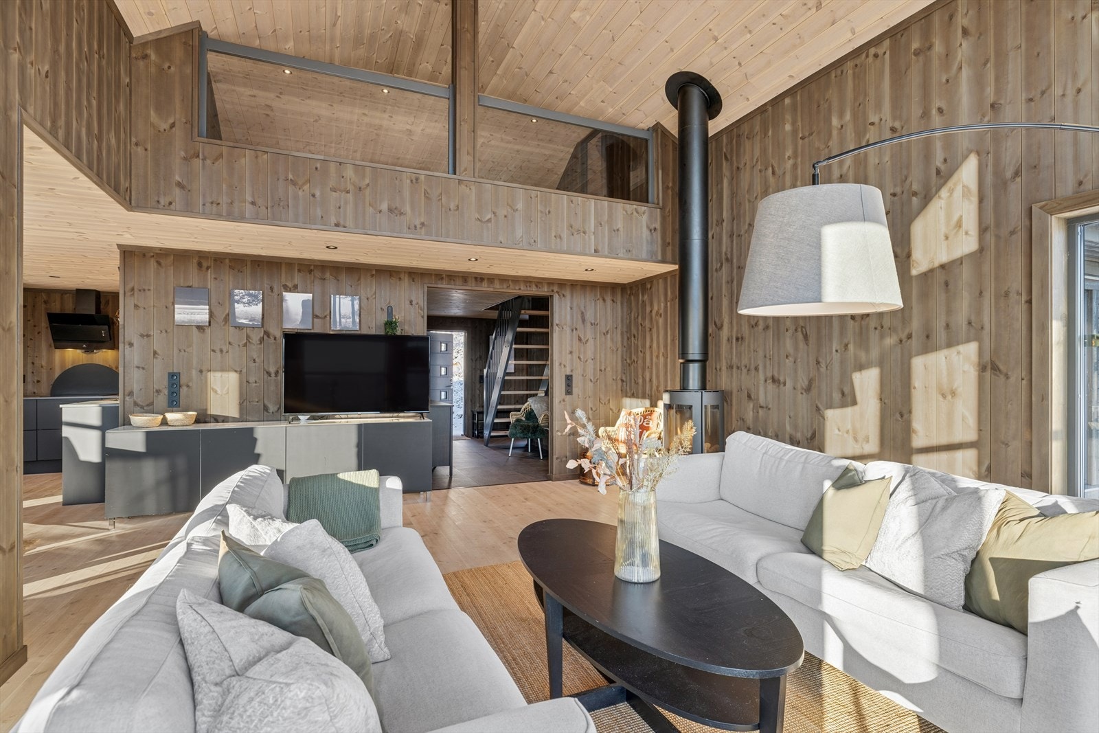 En moderne og stilren stue med god takhøyde som bidrar til en åpen og luftig atmosfære Galleribilde