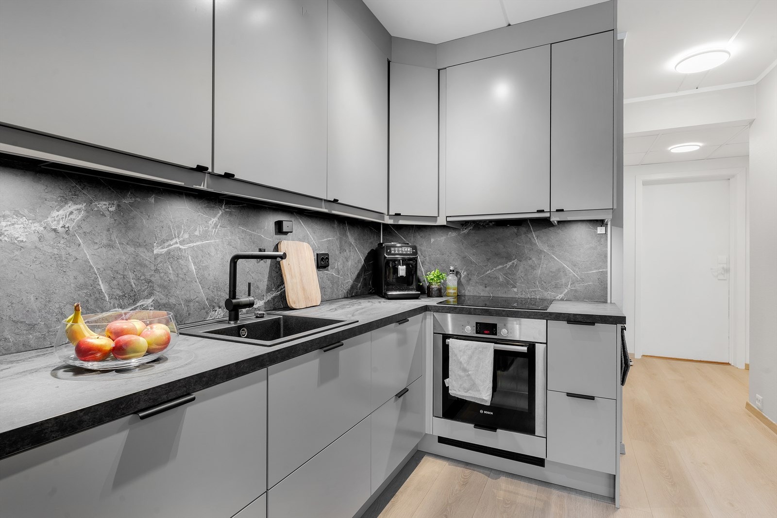 Pent kjøkken med integrerte hvitevarer og rikelig skap- og benkeplass. Galleribilde