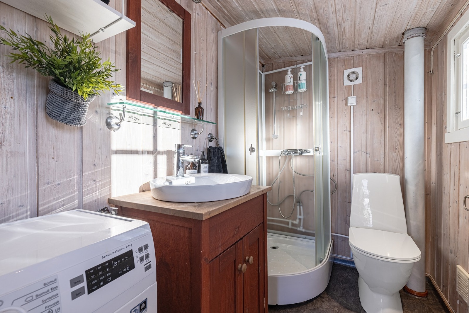 Delikat baderom med dusjkabinett og opplegg for vaskemaskin. Galleribilde