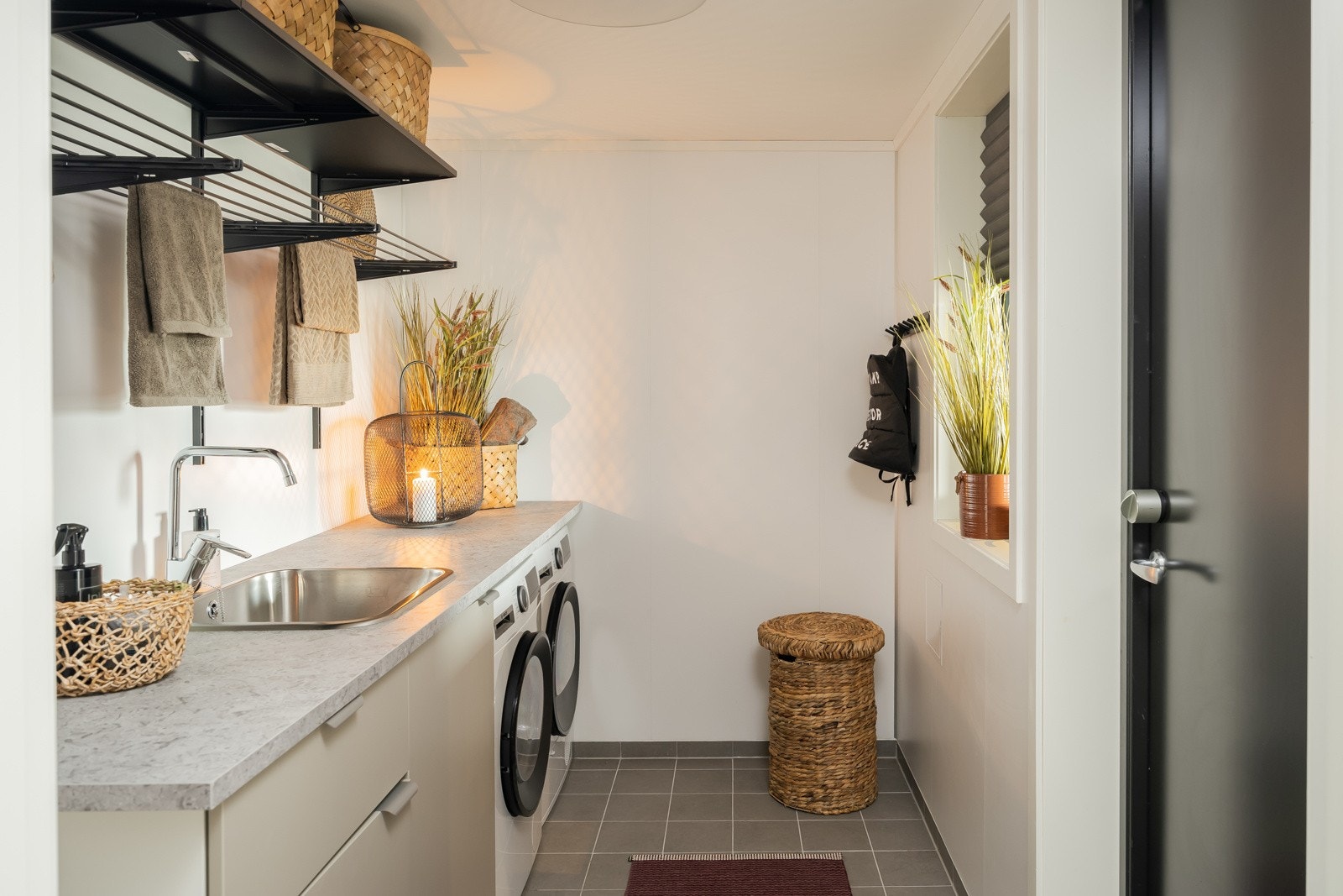 Velutstyrt vaskerom med gulvvarme, tilpassede skap- og skuffeseksjoner, opplegg for vaskemaskin og servant med benk og underskap. Galleribilde