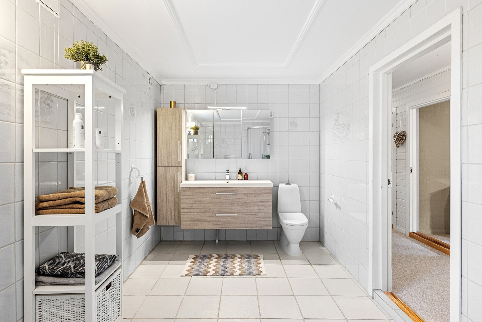 Romslig baderom med flislagte overflater og behagelig gulvvarme. Badet er innredet med moderne servantinnredning, vegghengt skap og speil med belysning. Galleribilde