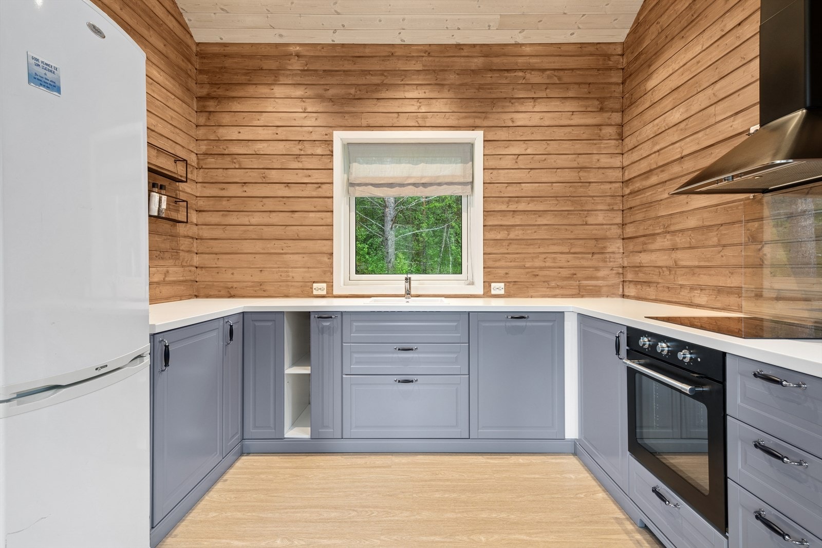 Kjøkkenet har innredning med profilerte grå fronter og en hvit laminat benkeplate. Galleribilde