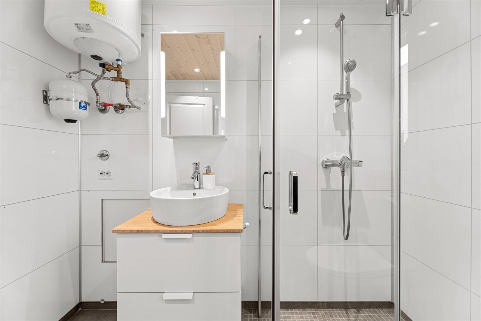 Badet har flislagt gulv med behagelig gulvvarme, og vegger med moderne baderomsplater som gir et rent og stilfullt uttrykk. Galleribilde