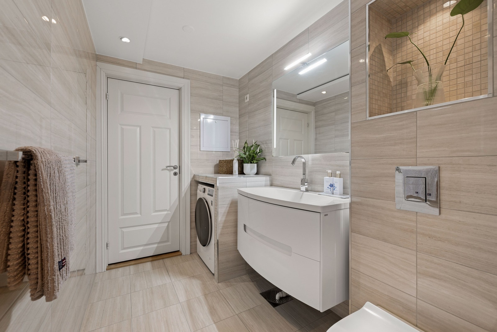 Badet er innredet med vegghengt toalett og servantinnredning med ovenpåliggende vask. Det er speil m/lys over servant. Galleribilde