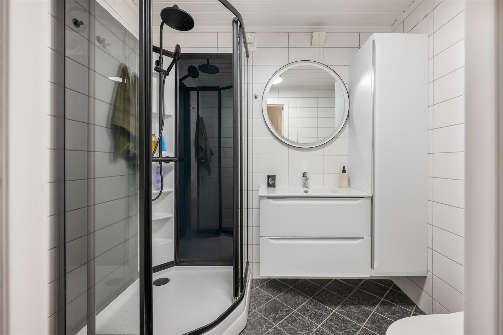 Pent flislagt bad med dusjhjørne, moderne baderomsinnredning og nøytrale fargevalg. Galleribilde