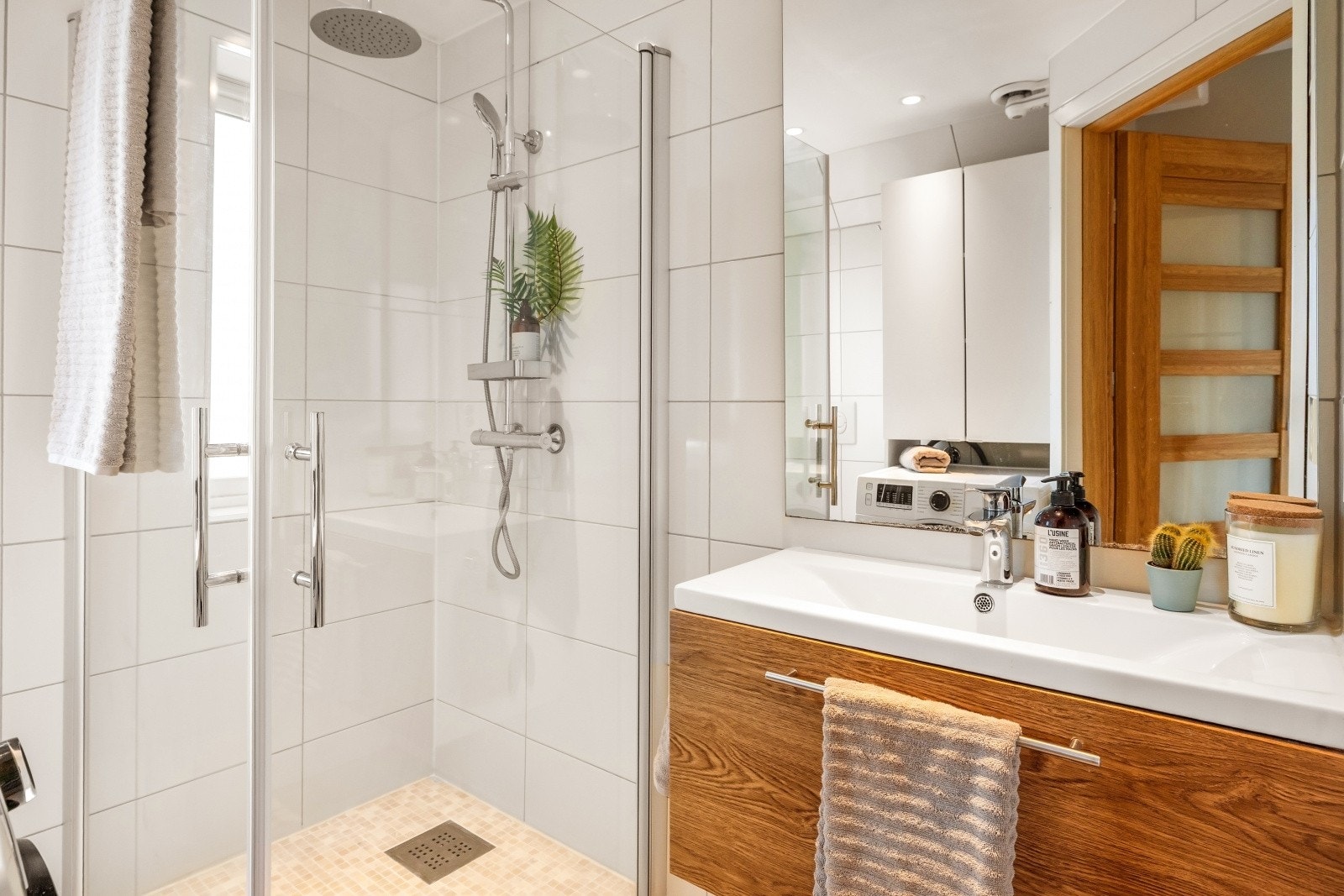 Flott bad med servant med skuffer, vegghengt toalett, dusj med glassfolddører og opplegg for vaskemaskin. Badet er utført med rør-i-rør-system Galleribilde