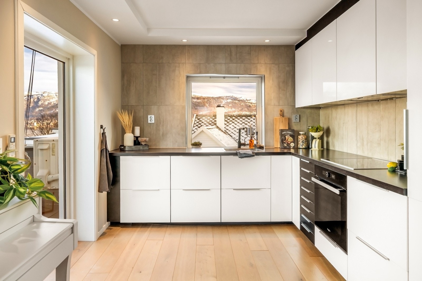 Funksjonelt kjøkken med laminat benkeplate, platetopp og ventilator med avtrekk ut Galleribilde