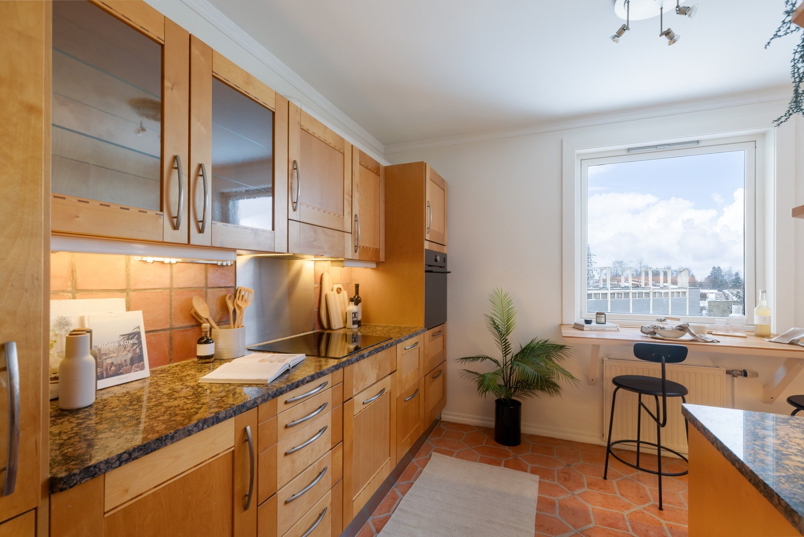 Separat kjøkken med Norema innredning med finerte, 1-speils profilerte fronter og benkeplate i stein med fliser over. Galleribilde