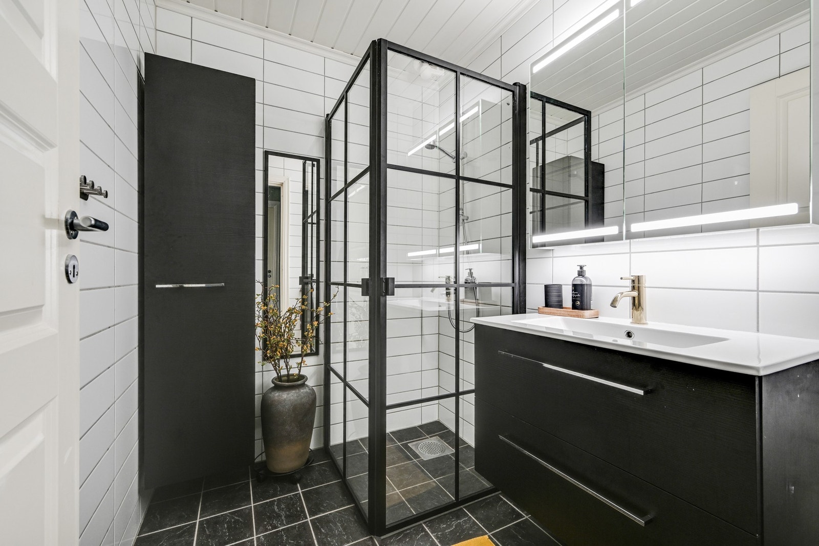 Badet har et moderne preg med lekkert dusjhjørne, servant med underskuffer og et høyskap. Over servanten er det vegghengt speil med integrert belysning Galleribilde