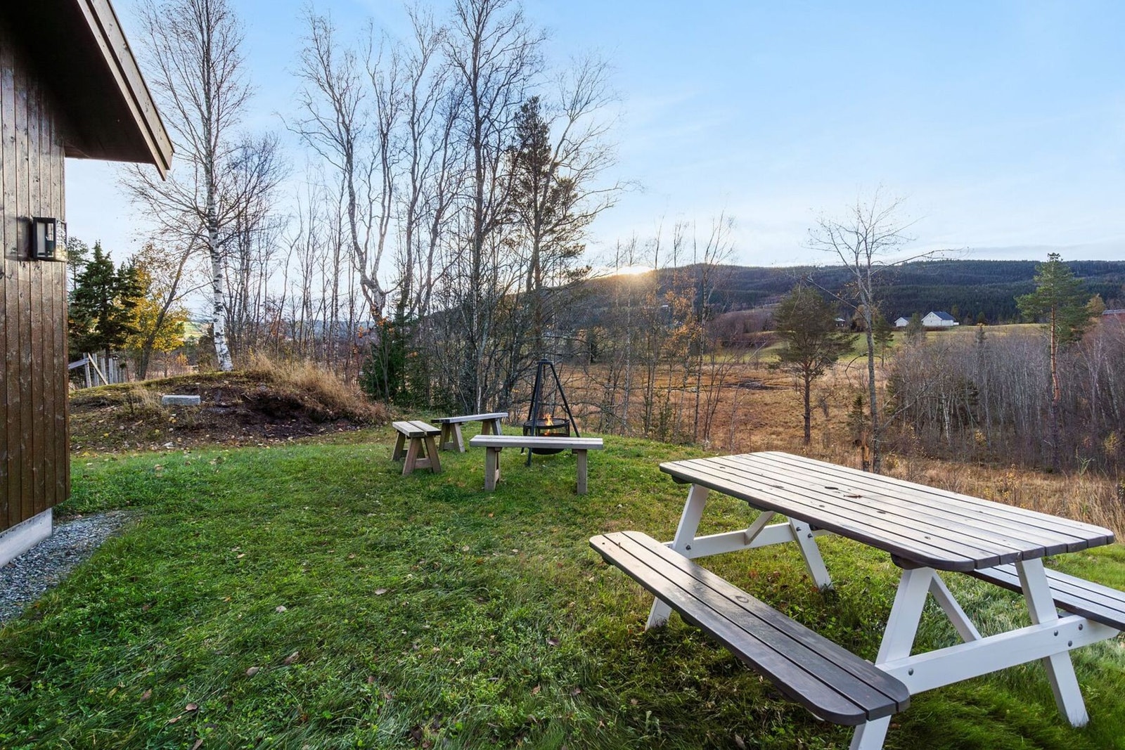 Pent opparbeidet uteområde ved inngangspartiet med bålpanne og benker. Galleribilde