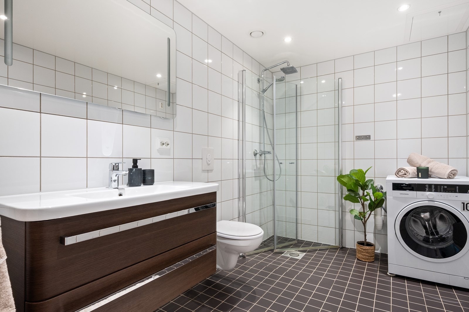 Badet i 2.etasje er helfliset og er innredet med baderomsinnredning med servant, vegghengt toalett, dusj og opplegg til vaskemaskin. Galleribilde