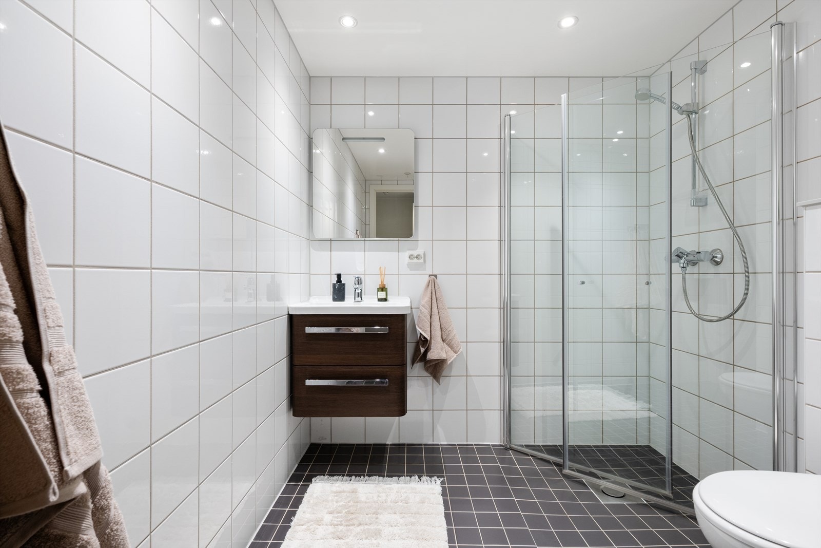 Badet i 1.etasje er også helfliset og er innredet med baderomsinnredning med servant, vegghengt toalett og dusj. Galleribilde