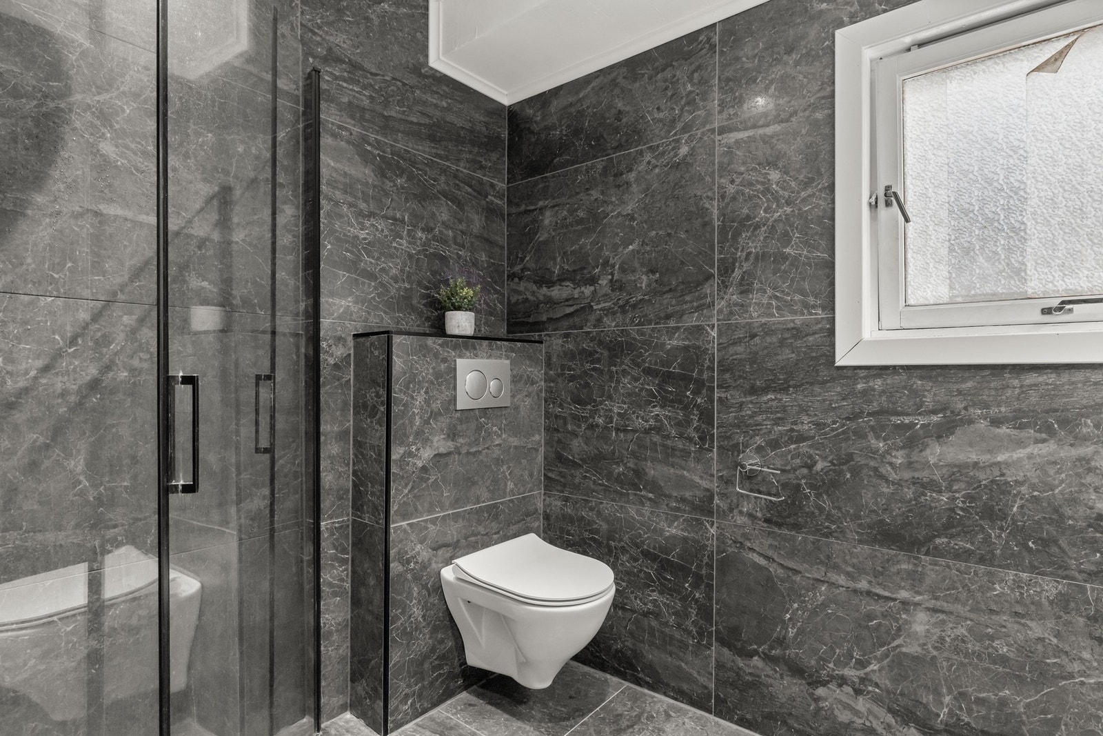 Badet i 1. etasje ble pusset opp i 2021 og er flislagt med gulvvarme. Rommet er innredet med dusj på gulv med glassvegger, vegghengt toalett, servant med skuffer og speilskap med belysning. Galleribilde