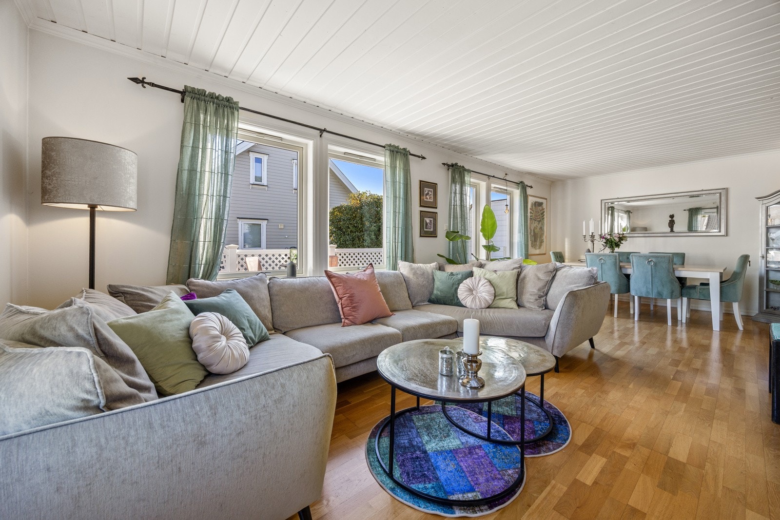 Lys, romslig og innbydende stue med store vindusflater som slipper inn rikelig med naturlig lys og skaper en behagelig atmosfære. Rommet har lysmalte, slette veggflater og parkett på gulv, noe som gir en moderne og tidløs stil. Galleribilde