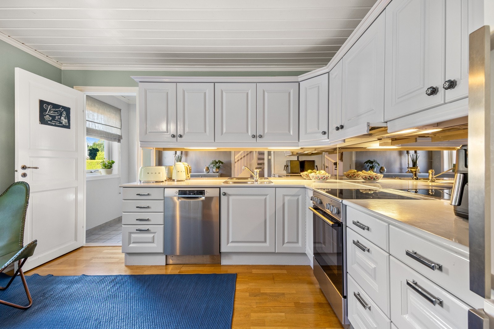 Lyst og koselig separat kjøkken i klassisk stil fra JKE, med profilerte, gråmalte fronter og en slitesterk laminatbenkeplate med nedfelt vaskekum i rustfritt stål. Galleribilde