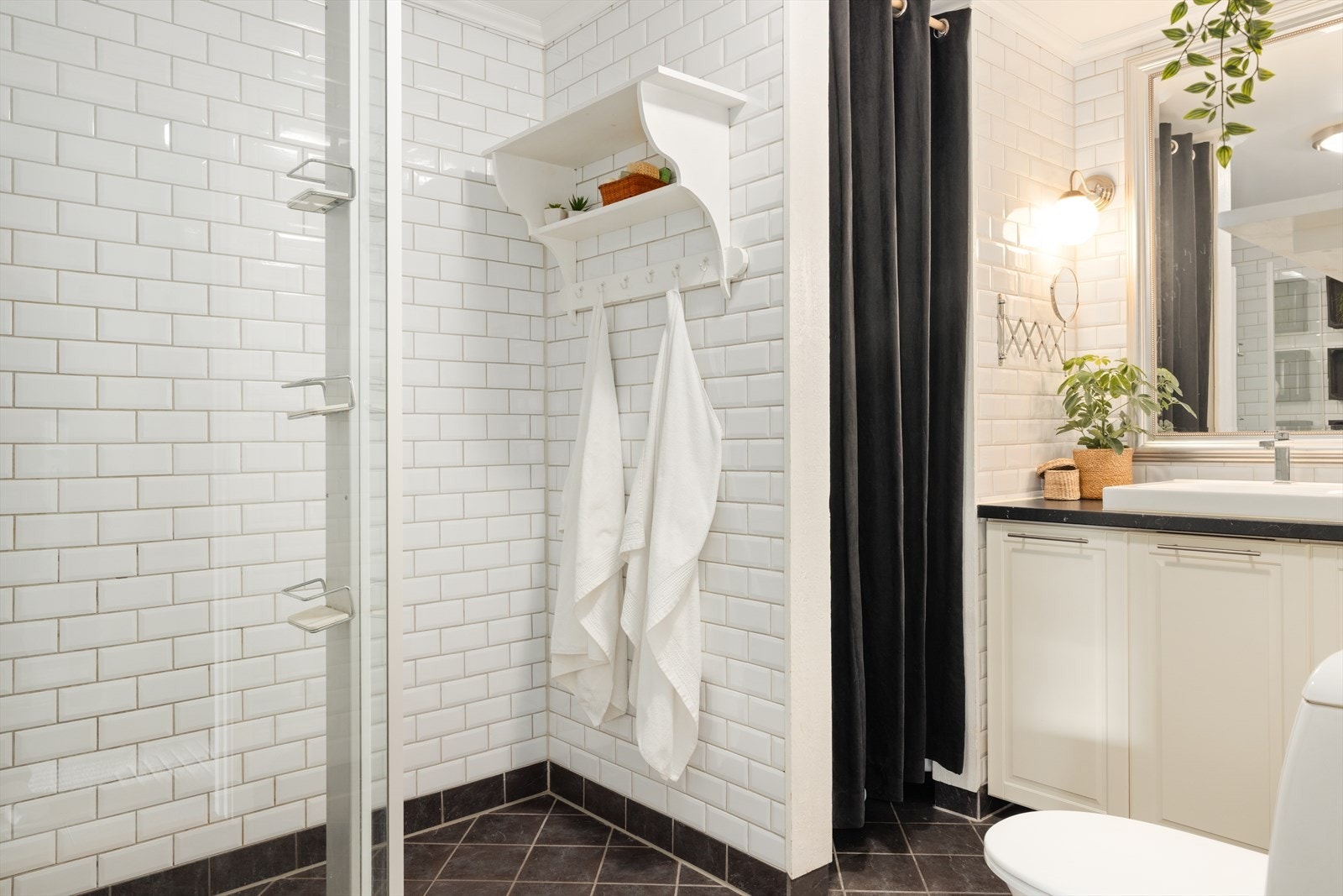 Badet inneholder toalett, helstøpt servant, skap under servant med profilerte fronter, dusjvegger i klart glass, opplegg for vaskemaskin og varmtvannsbereder Galleribilde