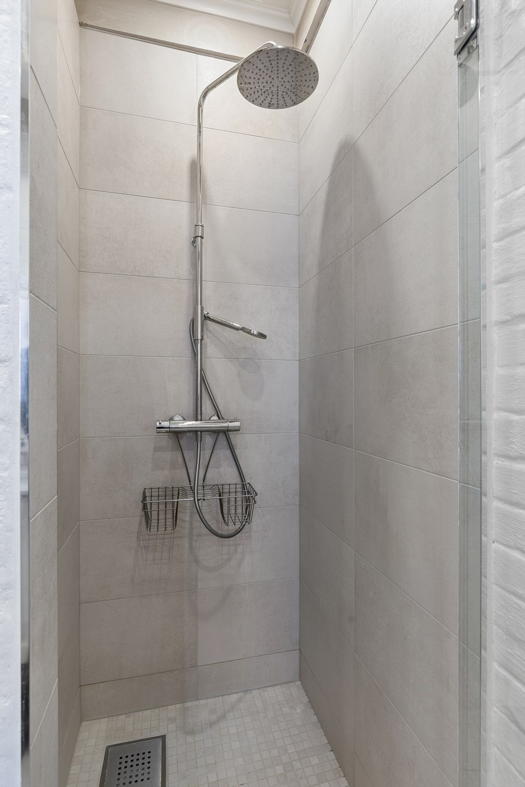 Dusjnisje med fliser på gulv. Det er ventilasjon via motorisert avtrekk i rommet. Galleribilde