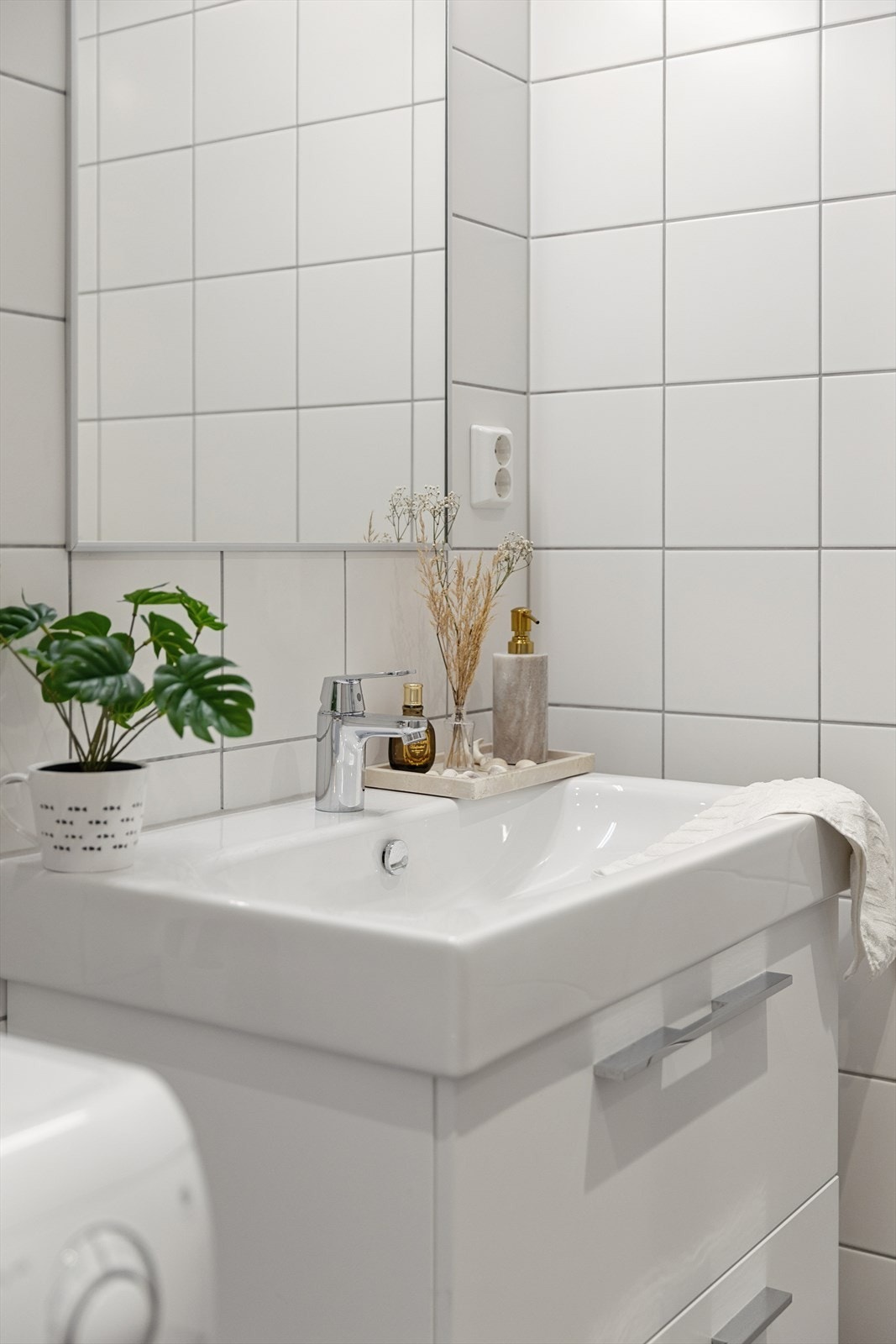 Baderom med dusjhjørne med innfellbare glassdører, vegghengt toalett, servant med underskap og opplegg for vaskemaskin/tørketrommel. Galleribilde