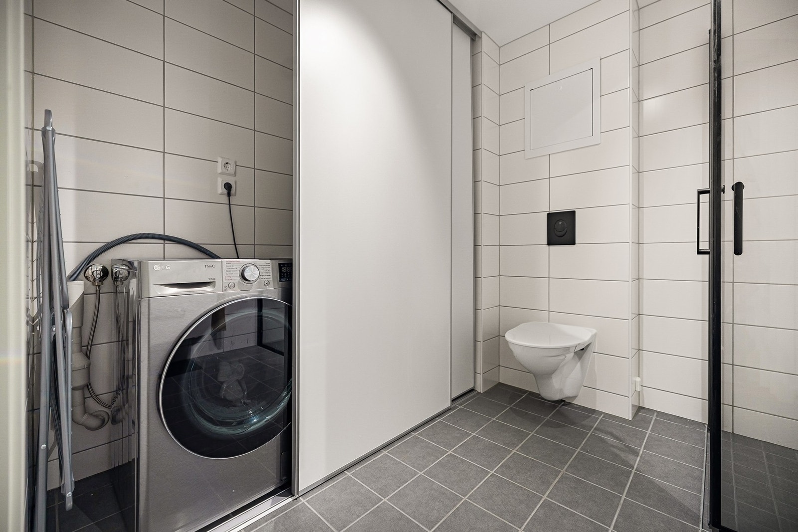 Varmtvannsbereder, vannskap og opplegg for vaskemaskin er plassert bak skyvedørsinnredning. Galleribilde